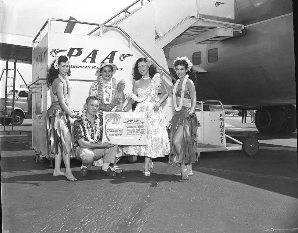 1954 Hula Girls pose by the stairway to a Pan Am Boeing 377 Stratocruiser.